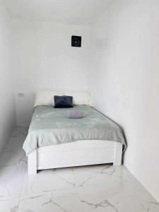 a white bed in a room with a white wall at JMary Stayhouse in Nopol