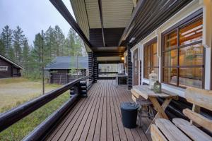 a porch of a cabin with a bench and a table at Villa Aurora - Valkea Homes in Pelkosenniemi