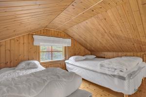 two beds in a wooden cabin with a window at Villa Aurora - Valkea Homes in Pelkosenniemi