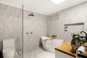 a bathroom with a white tub and a shower at Kirra Beach Escape - Pool Tennis Pets Near Airport in Gold Coast