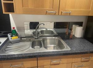 a stainless steel sink in a kitchen with wooden cabinets at Flat 2 Meadow view in Hurst
