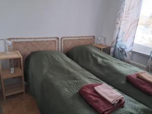 Una cama con dos sábanas y toallas verdes encima. en Kiva asunto Vääksyn kanavalla, en Asikkala