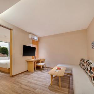 a hotel room with a couch and a tv at Model J Hotel Jakarta Central Park 曼居酒店 雅加达中央公园店 in Jakarta