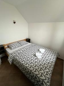 a bedroom with a bed with a black and white comforter at Apartmani Rajić, Tara in Kaludjerske Bare
