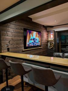 a bar with chairs and a television on a wall at The Nook Hakuba in Hakuba