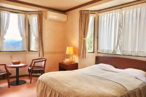 a bedroom with a bed and a chair and windows at 風薫る宿 伊豆星の舞 in Ito +52 photos