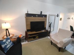a living room with a tv and a couch and a chair at Apto 3 Dormitórios, 2 Vagas, Completíssimo, Central, próx Mar in Torres