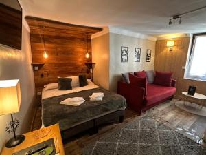 a bedroom with a bed and a red couch at Auberge de la Paix in Briançon