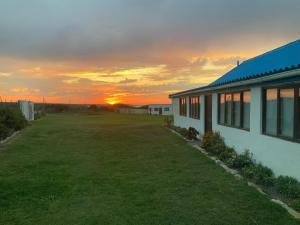 a house with a yard with the sunset in the background at Kuierbos in Gouritzmond