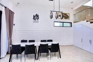 a dining room with a white table and black chairs at Villa The Romance in Tagalbato