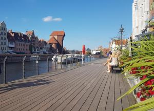 a woman sitting on a bench next to a river at Brzeziny Dworska 24 in Gdańsk
