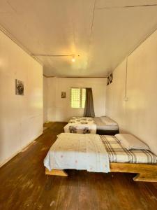 two beds in a room with wooden floors at Rustic B&B in Ranau