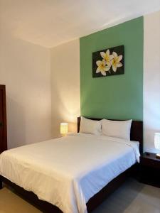 a bedroom with a white bed with a green wall at Willy Homestay in Uluwatu +26 photos