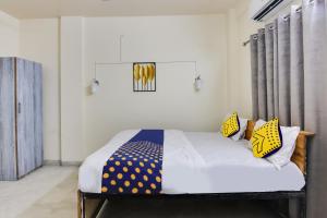 a bedroom with a bed with yellow and blue pillows at SPOT ON Hotel Blue Moon in Nagpur