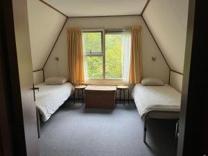 エルスペートにあるDe Boomkleverのベッド2台と窓が備わる屋根裏部屋です。
