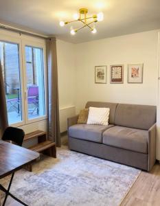 a living room with a couch and a table at Cosy 2 pièces terrasse 15 minutes de Paris in Bagneux