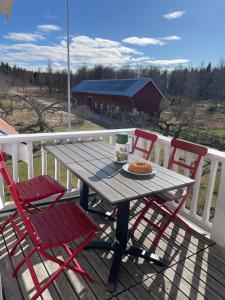 a picnic table with two chairs on a deck with a view at Accommodation near lake and forest including rowing boat in Tranås