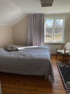 a bedroom with a bed and a window and a chair at Accommodation near lake and forest including rowing boat in Tranås