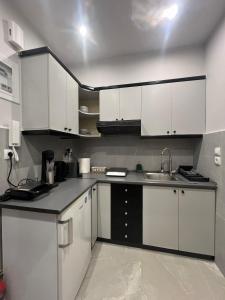 Una cocina con gabinetes blancos y un fregadero. en Skylan Studio, en Larisa