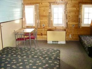 a room with a bed and a table and two windows at Horská chalupa u skiareálu in Horní Malá Úpa