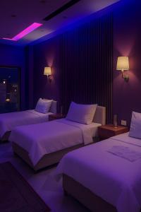 two beds in a room with purple lighting at ayla pyramids inn in Nazlat as Sammān +38 photos