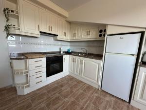 a kitchen with white cabinets and a white refrigerator at Apartamento Balea - San Vicente do Mar in Balea