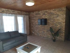 a living room with a couch and a tv on a brick wall at BushWave in Jeffreys Bay