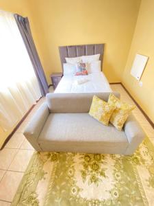 a bed with a couch in a room at Gabriel cottage in Mbabane