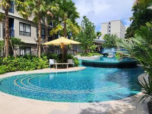 a swimming pool with a table and an umbrella at Cozy Palm Haven apartment in Kathu