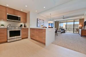 a large kitchen with wooden cabinets and a living room at Whaler 859 BeachFront Luxury Condo w Ocean Views in Lahaina