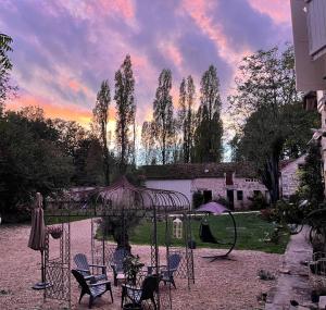un grupo de sillas y un paraguas en un patio en Le petit jardin du Coudray, en Étréchy