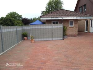 a fence in front of a house with a brick driveway at Apartment Emma in Sandkrug in Hatten