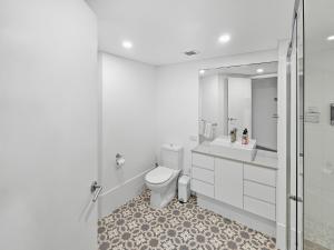 a white bathroom with a toilet and a sink at Seaside Sovereign Retreat in Caloundra +7 photos