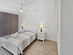 a white bedroom with a bed and two night stands at Seaside Sovereign Retreat in Caloundra
