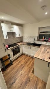 a kitchen with white cabinets and a wooden floor at Entire apartment in Waterloo, Crosby, Liverpool in Crosby +21 photos