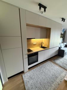 别拉什尼察Apartman Asi的厨房配有白色橱柜、水槽和地毯。 更多26张照片