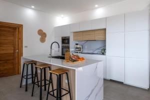 a kitchen with white cabinets and a counter with bar stools at Villa Orchidée Infinity pool & sea view 3BR in Amphoe Koh Samui