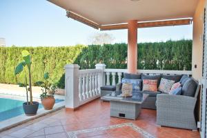 Un patio con un sofá y una piscina. en Your Paradise with Pool - 2 min from Beach, en Moncófar