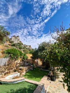 a garden with green grass and a blue sky at Casa Cerca del cielo in El Chorro
