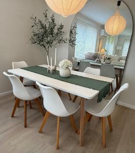 a dining room table with white chairs and a mirror at Cozy Stay in Forster in Forster