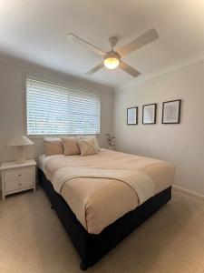 a bedroom with a bed with a ceiling fan at Cozy Stay in Forster in Forster