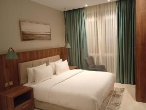 ein Schlafzimmer mit einem großen weißen Bett und einem Stuhl in der Unterkunft شُقَقُ دُخُولٍ ذاتِيّة in Quai