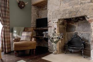 a living room with a stone fireplace with a chair and a television at Rose Apartment in Edinburgh