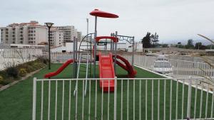 un parque infantil con un tobogán rojo y una sombrilla en La Serena Mini Departamento, en La Serena