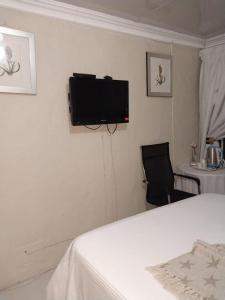 - une chambre avec un lit et une télévision murale dans l'établissement Liyoli Guesthouse, à Mthatha