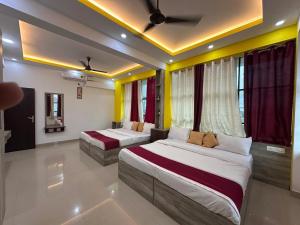 two beds in a room with yellow and red curtains at J TEN Residency in Meenangadi