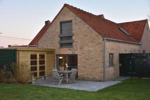 a brick house with a patio and a table at Vakantiewoning Cottage D&N te Passendale in Zonnebeke