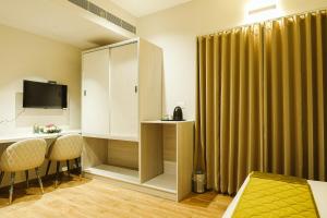 a room with a bed and a cabinet and two chairs at M Suites And Hotel in Cochin +19 photos