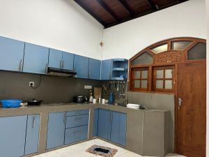 a kitchen with blue cabinets and a wooden door at Kashmir villa in Galle