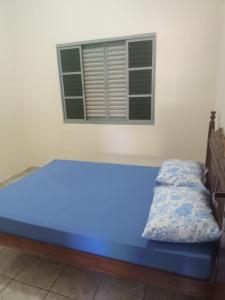 - un lit bleu dans une chambre avec fenêtre dans l'établissement Casa temporada São Roque - MG, à São Roque de Minas